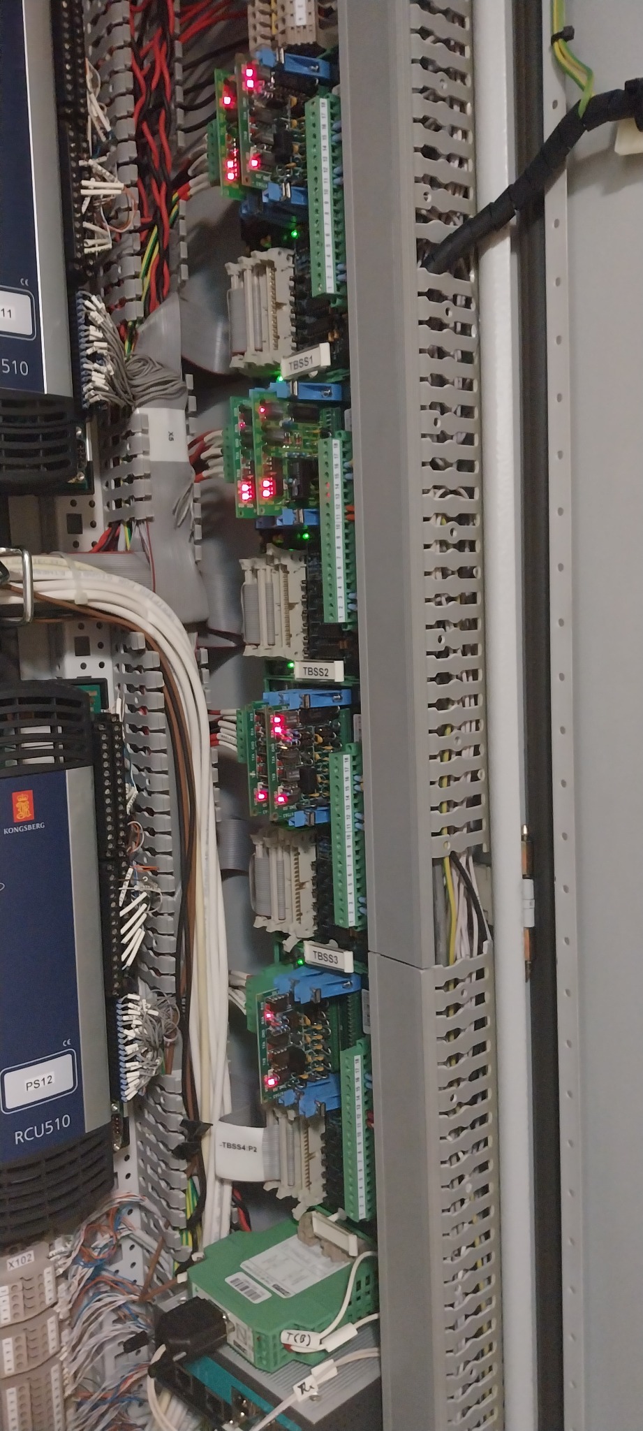 Panel sterowania z modułami TBSS1, TBSS2, TBSS3, TBSS4 P2, licznymi przewodami i elementami elektronicznymi w szarej obudowie. Widoczne diody sygnalizacyjne.