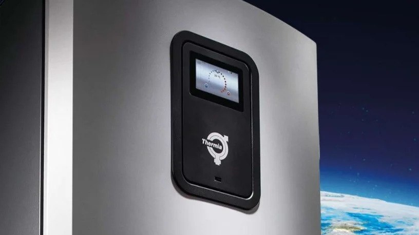 Szara pompa ciepła Thermia z czarnym panelem sterowania, na tle ciemnego nieba z gwiazdami i fragmentem Ziemi. Widoczny ekran z temperaturą.