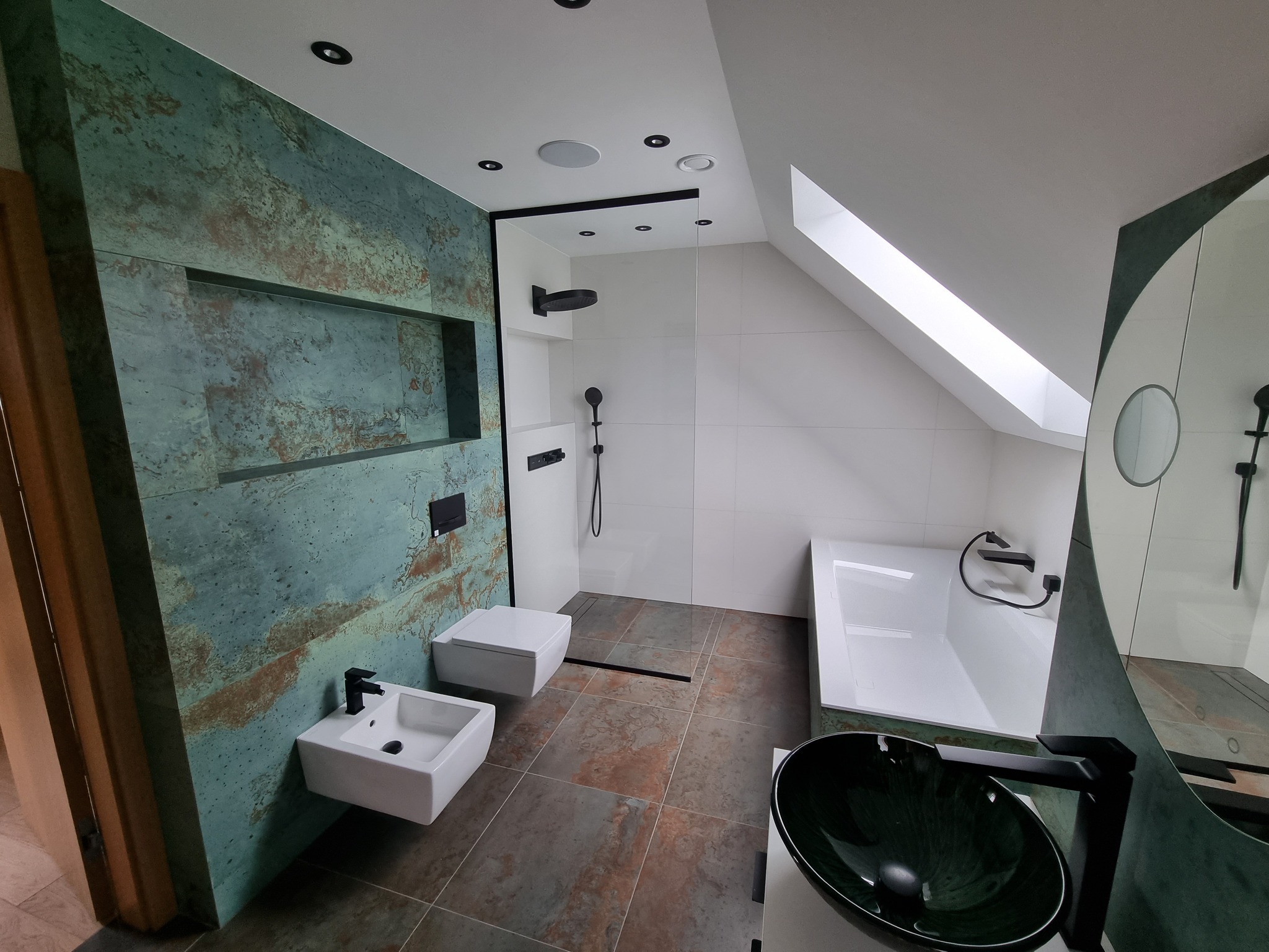 Nowoczesna łazienka na poddaszu z akcentem turkusowej ściany i czarnymi detalami armatury. Kabina prysznicowa typu walk-in, umywalka nablatowa i podwieszana toaleta.