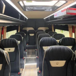 Wnętrze luksusowego busa marki Mercedes z czarnymi skórzanymi fotelami, beżowymi wstawkami i oświetleniem LED, gotowego do komfortowego przewozu osób.