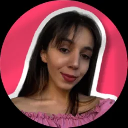 Portret uśmiechniętej kobiety z kolczykiem w nosie, w różowej bluzce z falbankami, na różowym tle z białą obwódką, w czarnym okręgu.