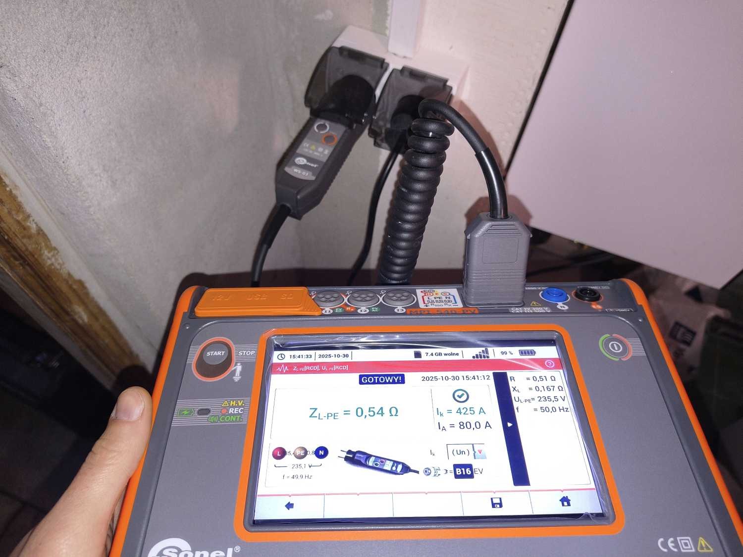 Miernik MPI-540PV Sonel w trakcie pomiarów elektrycznych w gniazdku. Ekran urządzenia pokazuje wyniki pomiarów impedancji pętli zwarcia ZL-PE.