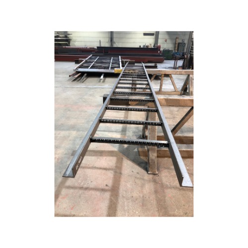 Metalowa drabina z antypoślizgowymi stopniami, wykonana w warsztacie. W tle widoczne profile i elementy konstrukcyjne.