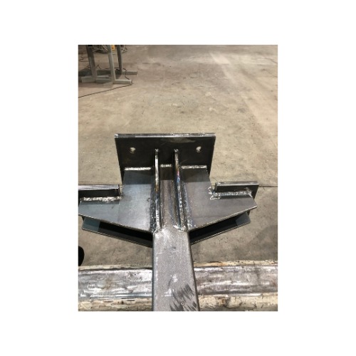 Metalowa konstrukcja spawana z blachy i profili, widoczne spoiny, surowy stan, na podłodze hali produkcyjnej, kąt ujęcia od dołu.