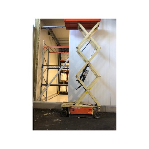 Podnośnik nożycowy z pomarańczową podstawą, używany w magazynie, blisko regałów. Biała ściana w tle.