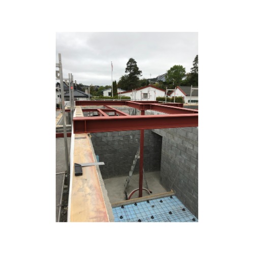 Konstrukcja stalowa w trakcie budowy domu, widoczne elementy zbrojenia i bloczki betonowe. Stalowe profile w kolorze czerwonym.