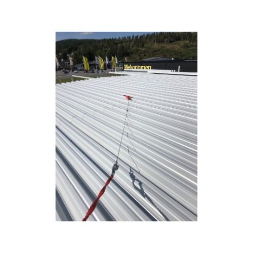 Biały, blaszany dach z zamocowanym systemem asekuracyjnym, z widocznymi elementami mocującymi i czerwoną liną. W tle budynek i drzewa.
