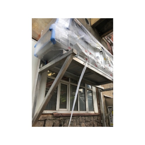 Stalowa konstrukcja wsporcza pod oknem, prawdopodobnie spawana, z zabezpieczonym urządzeniem na górze. Widoczny fragment elewacji z kamienia i okno.