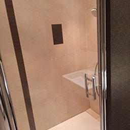 CrystalWave Cleaning - Czysta kabina prysznicowa z jasnymi płytkami i chromowanymi detalami. Widoczny brodzik, bateria i deszczownica. Minimalistyczny design, świeżo po sprzątaniu.