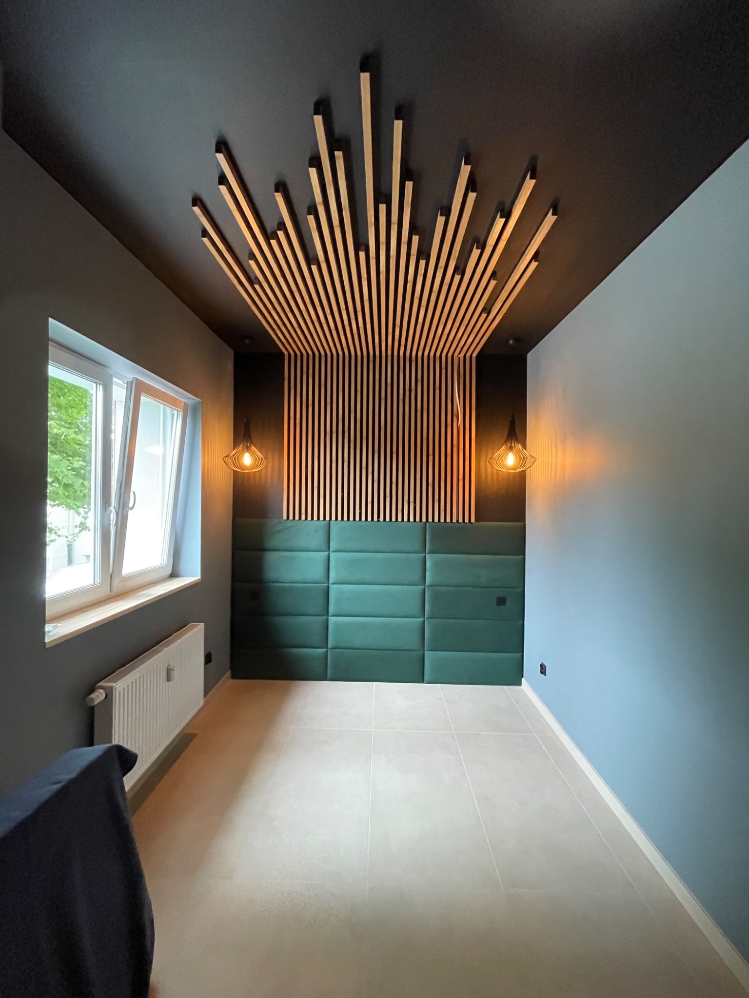 Nowoczesne wnętrze: zielony panel tapicerowany, drewniana dekoracja sufitu, lampy wiszące. Minimalistyczny design z akcentem na detale i kolorystykę ścian.