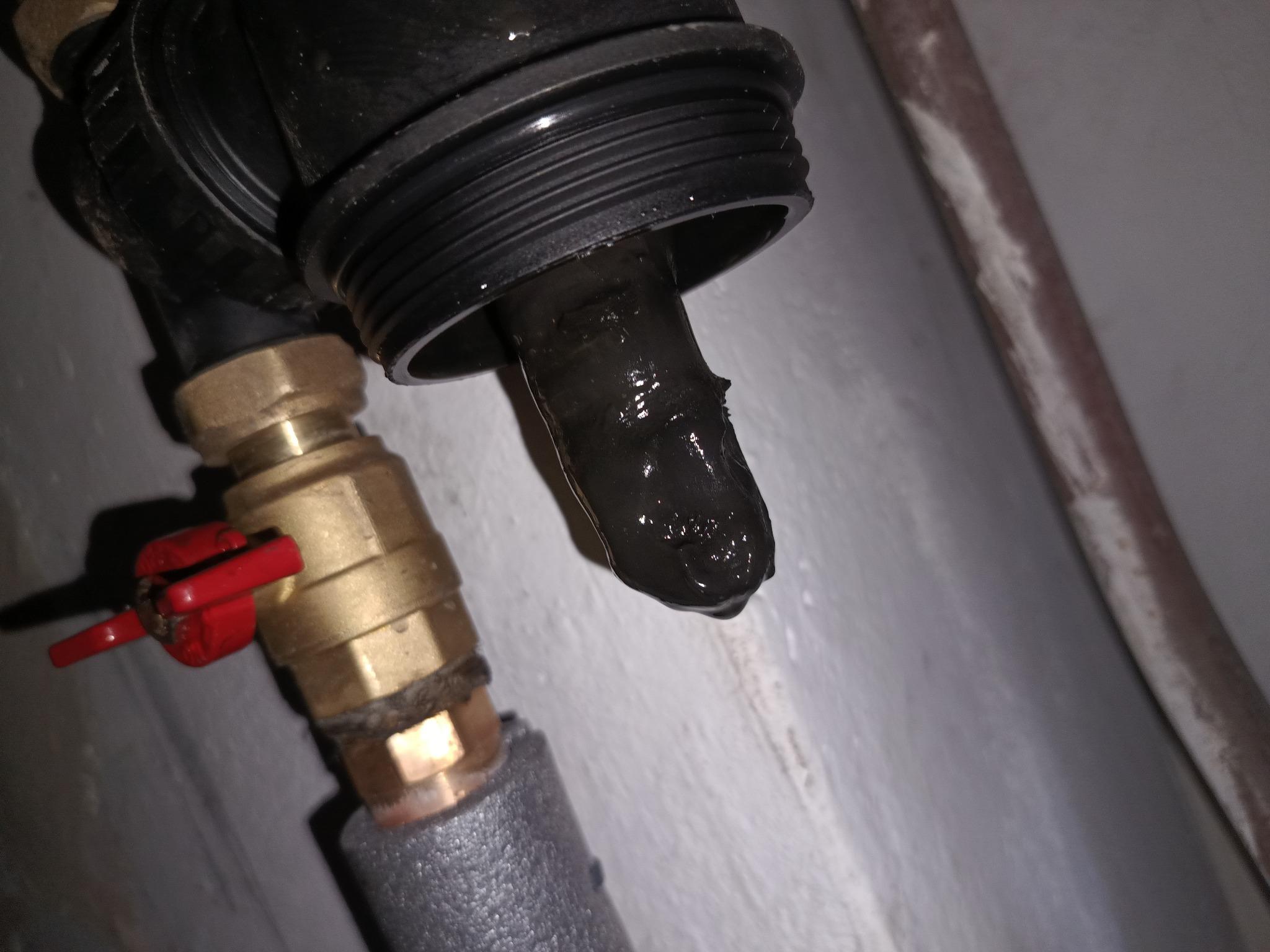 Zanieczyszczony filtr instalacji CO z widocznymi osadami i zanieczyszczeniami, element instalacji z zaworem kulowym i rurą w izolacji, ujęcie z bliska.