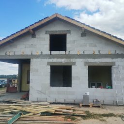 Bartłomiej Skonieczny - Budowa domu z betonu komórkowego w trakcie realizacji. Widoczne niezadaszone okna, drewniane elementy konstrukcji dachu i porozrzucane deski.