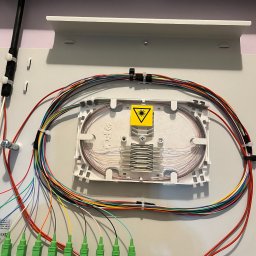 LinkSat Serwis Anten i Światłowodów - Zamknięta skrzynka światłowodowa z kolorowymi kablami i żółtą naklejką ostrzegawczą. Precyzyjne ułożenie włókien wewnątrz. Estetyczne wykończenie instalacji.