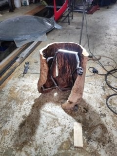 Unikatowa lampa z pnia drzewa w surowym wnętrzu warsztatu. Widoczne narzędzia i oświetlenie robocze, podkreślające rękodzielniczy charakter projektu.