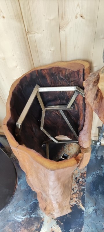 Unikatowy stolik kawowy: surowe drewno z ciemnym wnętrzem i metalową konstrukcją. Naturalny kształt pnia, widoczne słoje. Blat z żywicy epoksydowej i marmurowa podłoga.