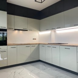 HolzForm Tomasz Jaśko - Nowoczesna kuchnia w odcieniach szarości i beżu z drewnianym blatem, oświetleniem LED i marmurową podłogą. Minimalistyczne uchwyty i zabudowa sprzętu AGD.