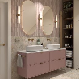 KRU Interiors - Nowoczesna łazienka z podwójną umywalką na różowej szafce, owalne lustra z podświetleniem LED, złota armatura i beżowe płytki. Minimalistyczny design.