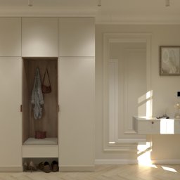 Jasna zabudowa przedpokoju z siedziskiem i wieszakami, uzupełniona o konsolę z lustrem i lampką. Parkiet w jodełkę, neutralna kolorystyka.