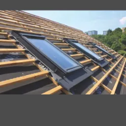 Montaż okien dachowych na drewnianej więźbie pokrytej membraną. Widok na trzy okna w trakcie instalacji, z widocznymi elementami konstrukcyjnymi dachu.