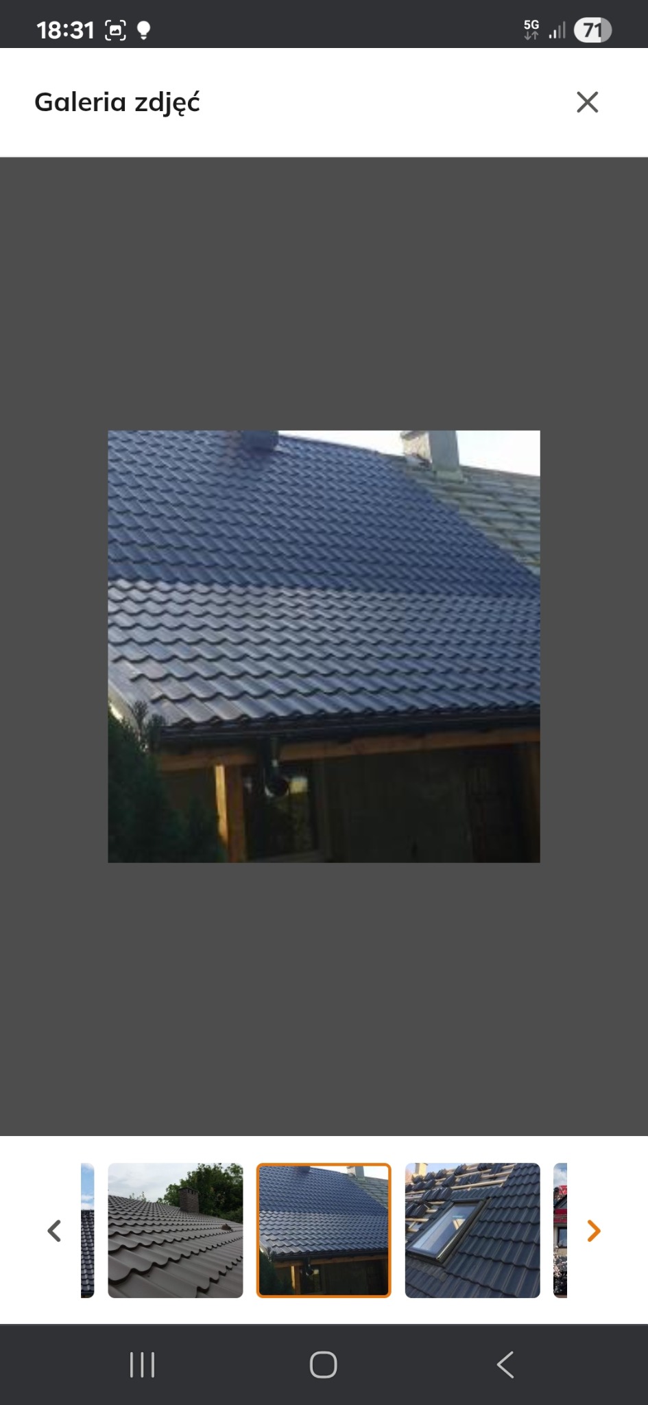 Ciemna blachodachówka na skośnym dachu domu jednorodzinnego, widok z dołu, fragment rynny. Na drugim planie komin.