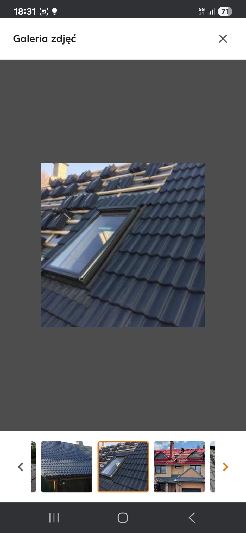 Częściowo pokryty dach z ciemnej dachówki z oknem dachowym; widoczne łaty i fragmenty niepokrytej połaci. Ujęcie z góry, w słoneczny dzień.