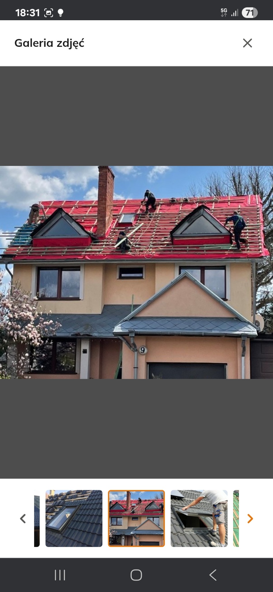 Dom z częściowo zdjętym dachem, widoczna czerwona membrana i ekipa dekarzy w trakcie pracy. Na dachu okna dachowe.