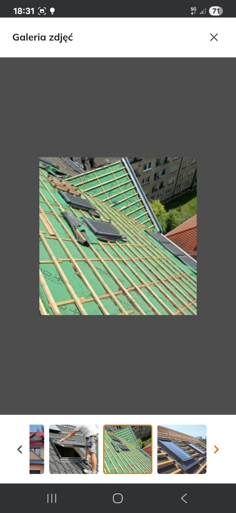 Konstrukcja dachu z zieloną membraną i zamontowanymi oknami dachowymi, widok z góry na tle budynku mieszkalnego.