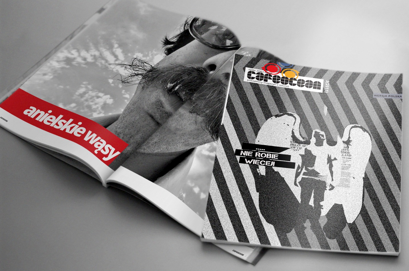 Otwarty magazyn 'Anielskie Wąsy' z wizerunkiem mężczyzny z wąsami, obok leży magazyn 'Careccean' z grafiką postaci ze skrzydłami. Druk w odcieniach szarości.