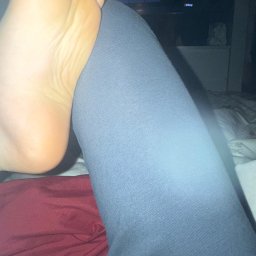 Szama-nka Catering - Stopa oparta na nodze w legginsach na tle łóżka i telewizora. Niestandardowy kadr, bliskie ujęcie, domowe otoczenie.