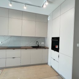 Kuchnia w kształcie literki L w popularnymi aktualnie frontami z płyty o wzorze kaszmirowym. Wszystkie akcesoria marki BLUM. Blat drewnopodobny. 