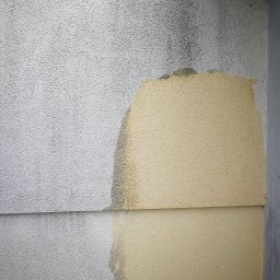 Rensar Polska - Fragment elewacji budynku z widocznymi śladami zabrudzeń i zacieków, częściowo umyta, ukazująca różnicę w kolorze i czystości powierzchni.
