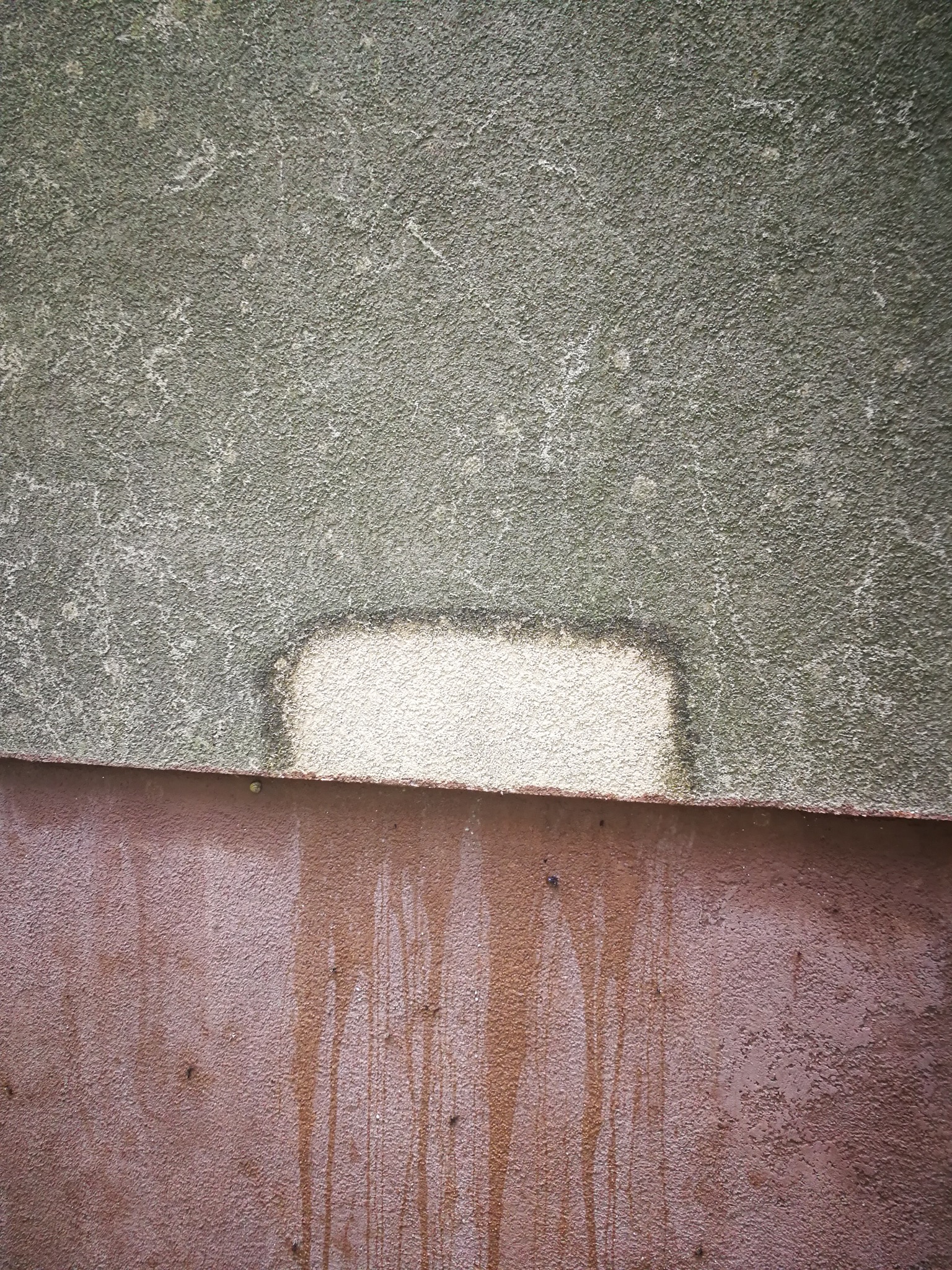 Fragment elewacji budynku z widocznym śladem po czyszczeniu, ukazujący różnicę w kolorze i strukturze przed i po zabiegu. Dolna część elewacji z zaciekami.