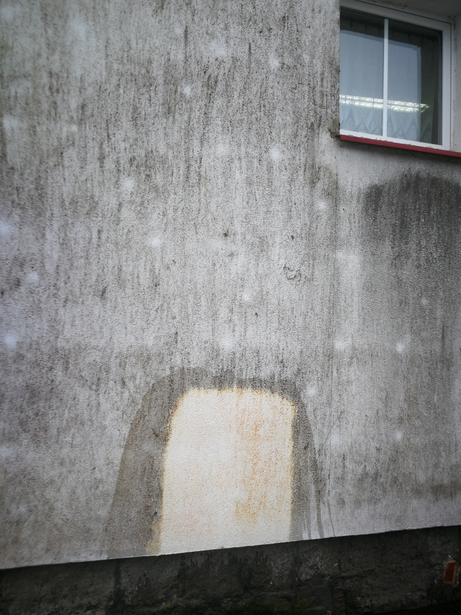 Fragment elewacji budynku w Krakowie, z widocznym oknem i wyraźnymi śladami zabrudzeń oraz miejscem po czyszczeniu, ukazującym różnicę w wyglądzie.