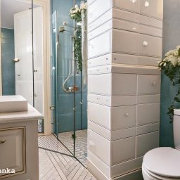 ZG Projekt Grzegorz Zapał - Jasna łazienka w stylu retro z błękitnymi ścianami, białą ceramiką i armaturą. Umywalka nablatowa, lustro w złotej ramie i dekoracja kwiatowa nadają wnętrzu elegancji.