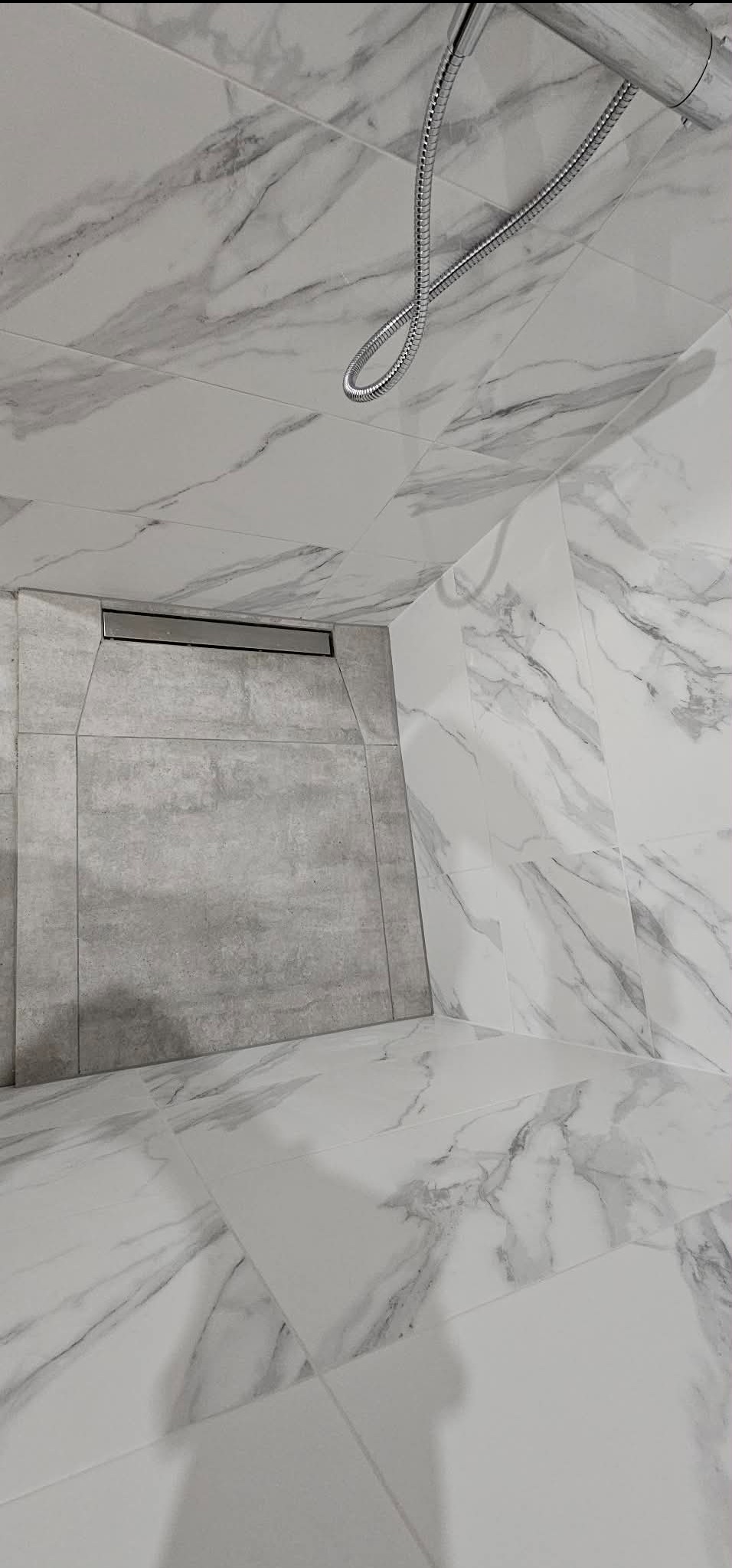 Nowoczesna kabina prysznicowa walk-in z odpływem liniowym i marmurowymi płytkami w Gdańsku. Minimalistyczny design, szara strefa prysznicowa.