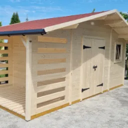 Drewniana altana z czerwonym dachem, otwartą przestrzenią z boku i zamkniętą częścią z drzwiami, umieszczona na kostce brukowej w ogrodzie.