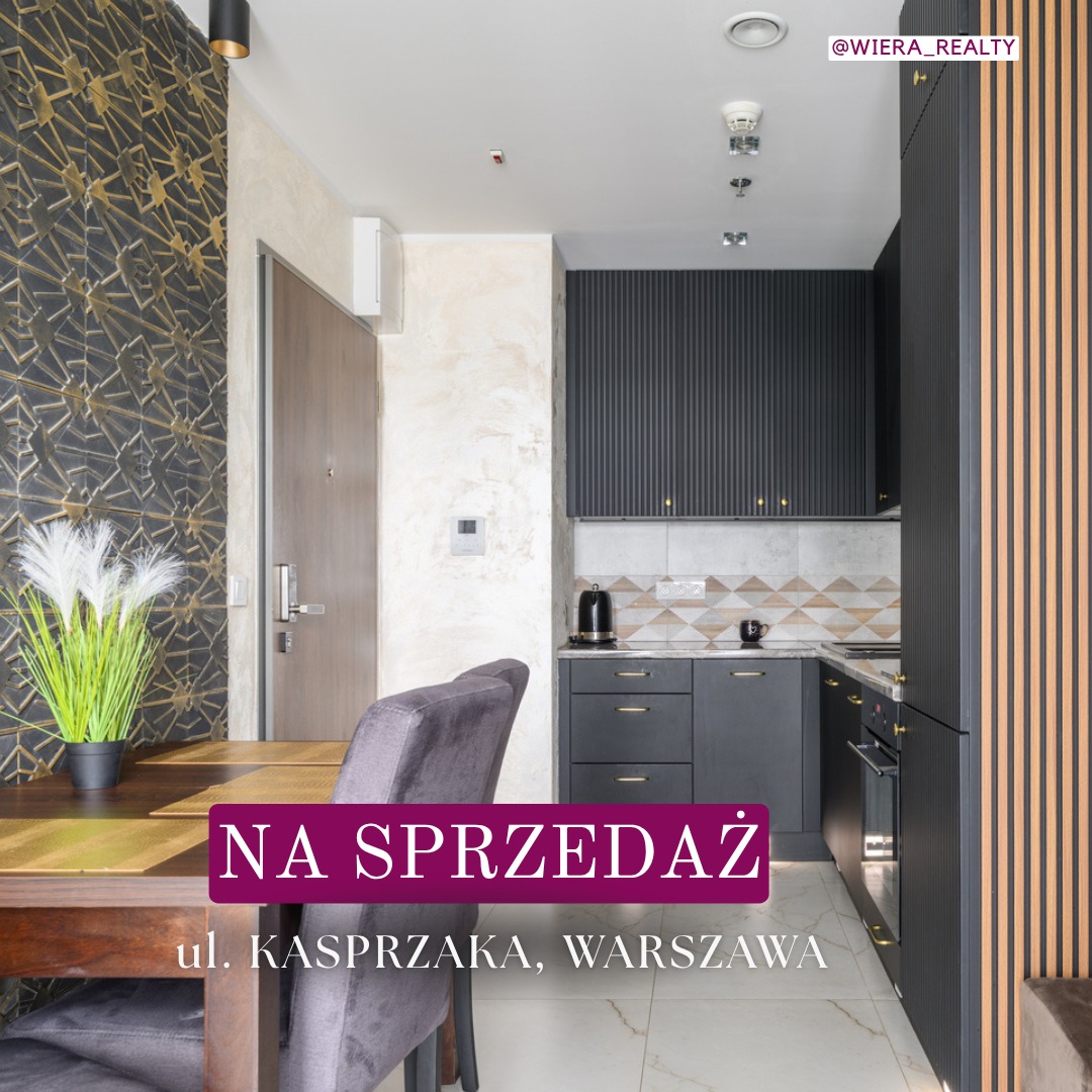 Nowoczesne wnętrze mieszkania na sprzedaż w Warszawie: salon z aneksem kuchennym, dekoracyjna ściana, drewniany stół, szare krzesło. Eleganckie wykończenie.
