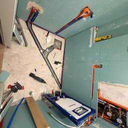 MIK-INSTAL Norbert Dembiński - Instalacja sanitarna w trakcie montażu: rury, stelaż podtynkowy WC Geberit, narzędzia. Ściany pokryte płytami gipsowo-kartonowymi. Widoczne podejścia wodne i kanalizacyjne.