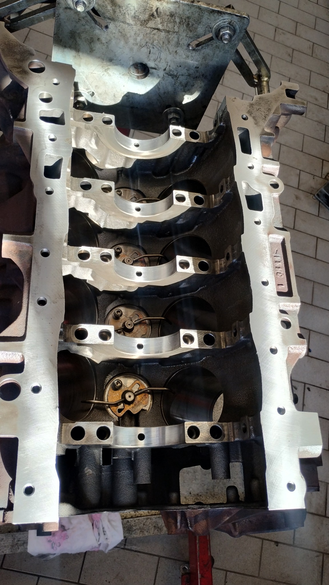 Otwarty blok silnika z widocznymi panewkami i elementami mocującymi, oświetlony światłem dziennym. Widoczne ślady użytkowania i smar.