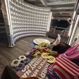 Probudka4you Monika Staros - Srebrna fotobudka z rekwizytami: okulary, kapelusze, zabawne napisy. Scena gotowa do sesji zdjęciowej na imprezie plenerowej z drewnianą podłogą i zadaszeniem.