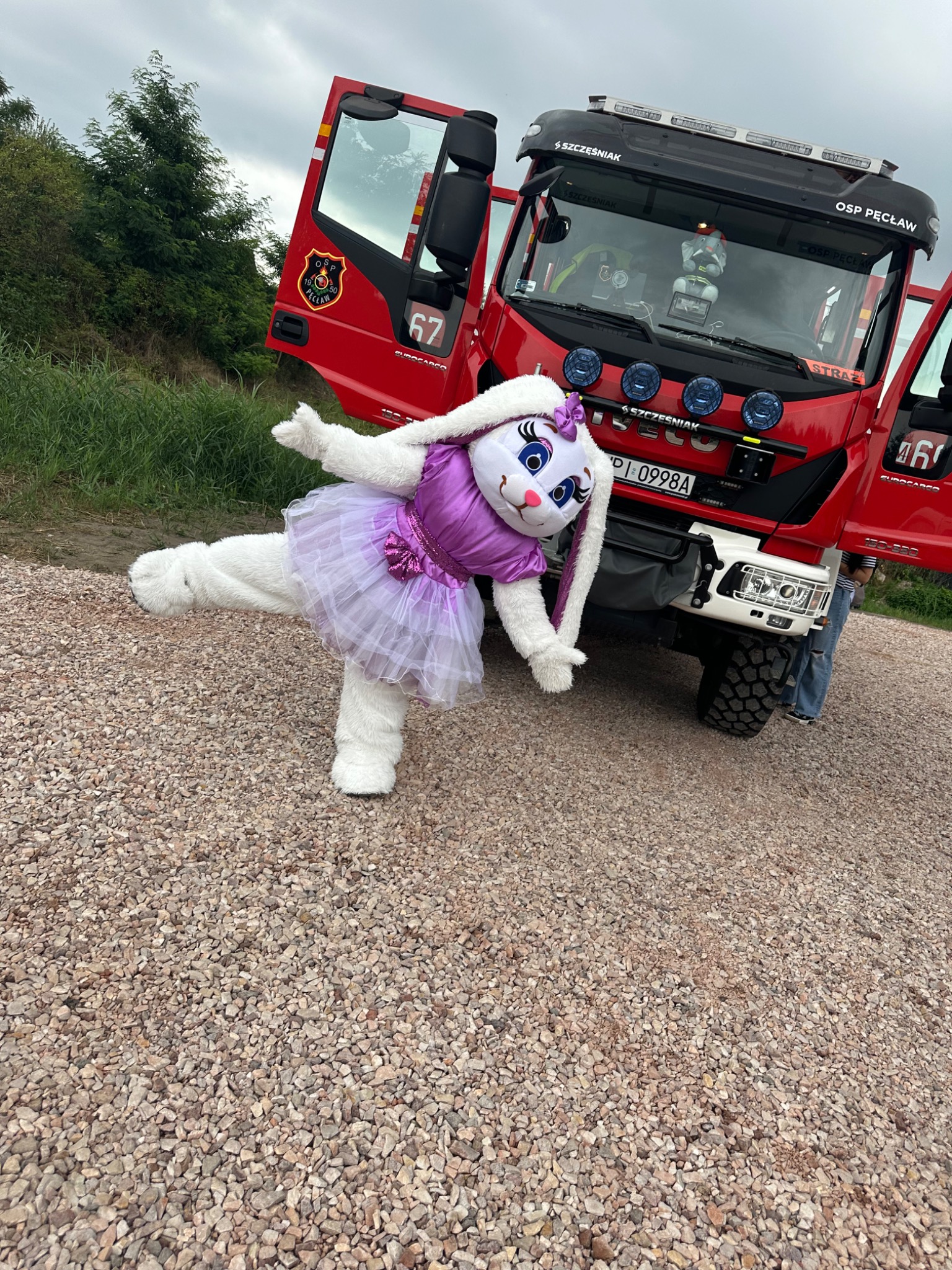 Animator w stroju królika baletnicy pozuje na tle wozu strażackiego OSP Pęcław, prezentując unikalną atrakcję eventową.
