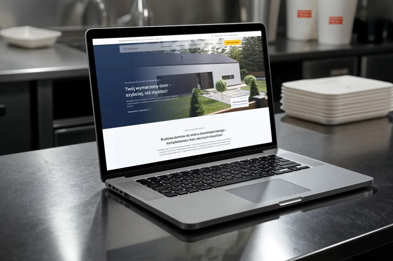 Laptop wyświetla stronę z nowoczesnym domem. Strona prezentuje ofertę budowy domów deweloperskich z wizualizacją 3D. Tło: stalowy blat kuchenny.