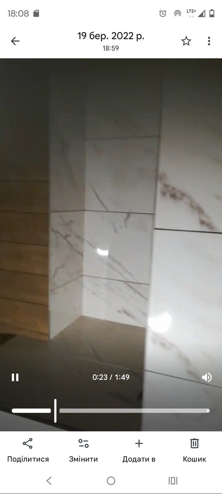 Wykończona łazienka z marmurowymi płytkami i drewnianymi panelami. Widoczny narożnik kabiny prysznicowej. Minimalistyczny design. Oświetlenie punktowe.