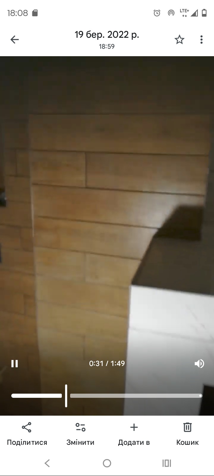 Wykończenie ściany drewnopodobnymi płytkami w łazience. Widoczny fragment białej umywalki. Ujęcie z bliska, ukazujące detale wykończenia.