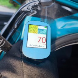 MICHAŁ KOWALÓWKA M&M BROKERS - Pomiar grubości lakieru na aucie miernikiem z wyświetlaczem wskazującym 70 um, stal ocynkowana. Widoczna ręka w czarnej rękawicy trzymająca urządzenie.