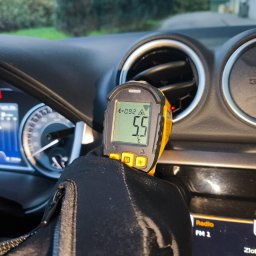 MICHAŁ KOWALÓWKA M&M BROKERS - Pomiar temperatury wylotu powietrza z klimatyzacji Suzuki Vitara za pomocą termometru laserowego. Wyświetlacz pokazuje 5.5°C. Widoczne kratki nawiewu i deska rozdzielcza.