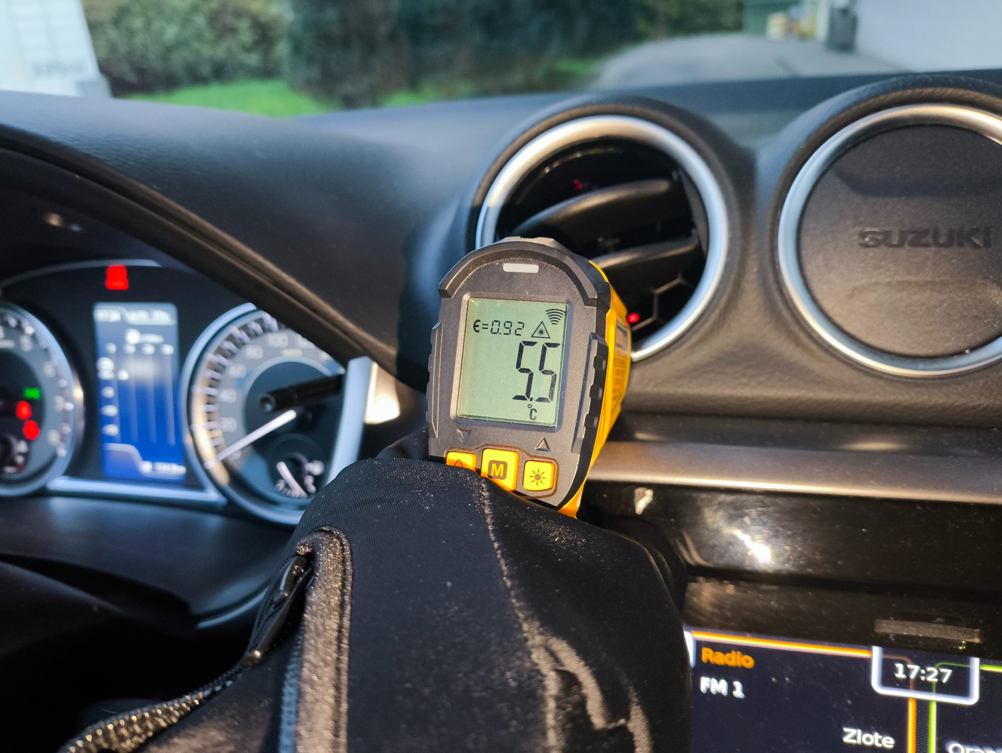 Pomiar temperatury wylotu powietrza z klimatyzacji Suzuki Vitara za pomocą termometru laserowego. Wyświetlacz pokazuje 5.5°C. Widoczne kratki nawiewu i deska rozdzielcza.