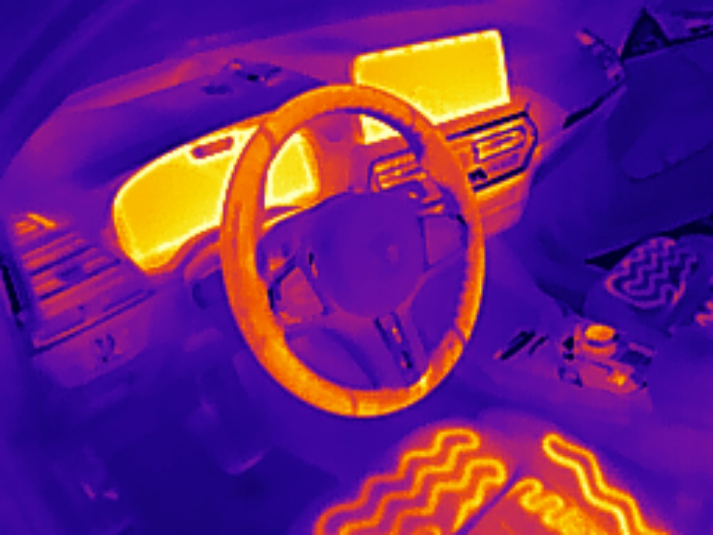 Termowizja wnętrza samochodu: kierownica, deska rozdzielcza i podgrzewane siedzenia w odcieniach fioletu i pomarańczu. Diagnostyka temperatury pojazdu.