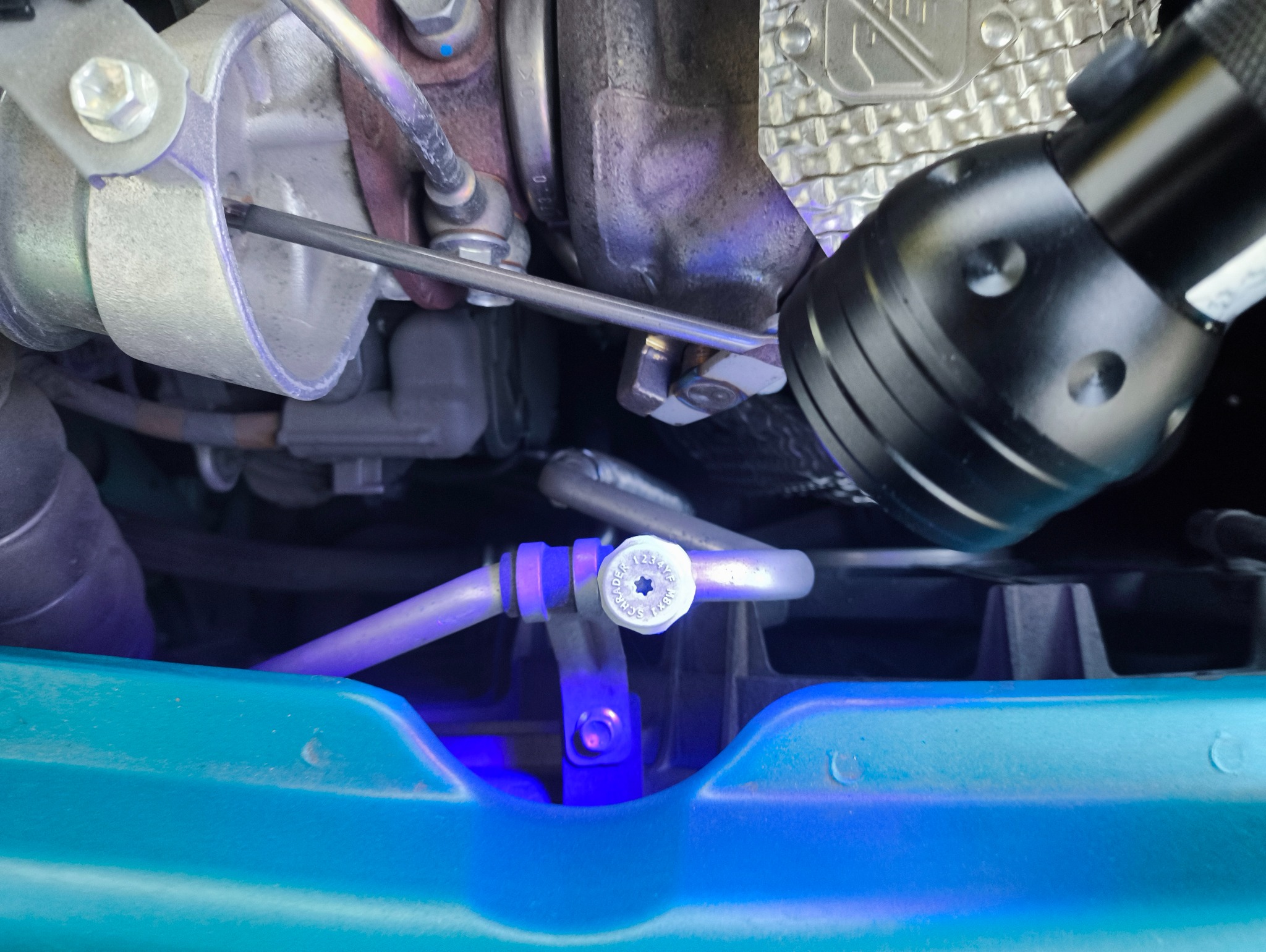 Diagnostyka klimatyzacji samochodowej w Krakowie: zbliżenie na zawór i rurkę klimatyzacji podświetlone lampą UV podczas serwisu.