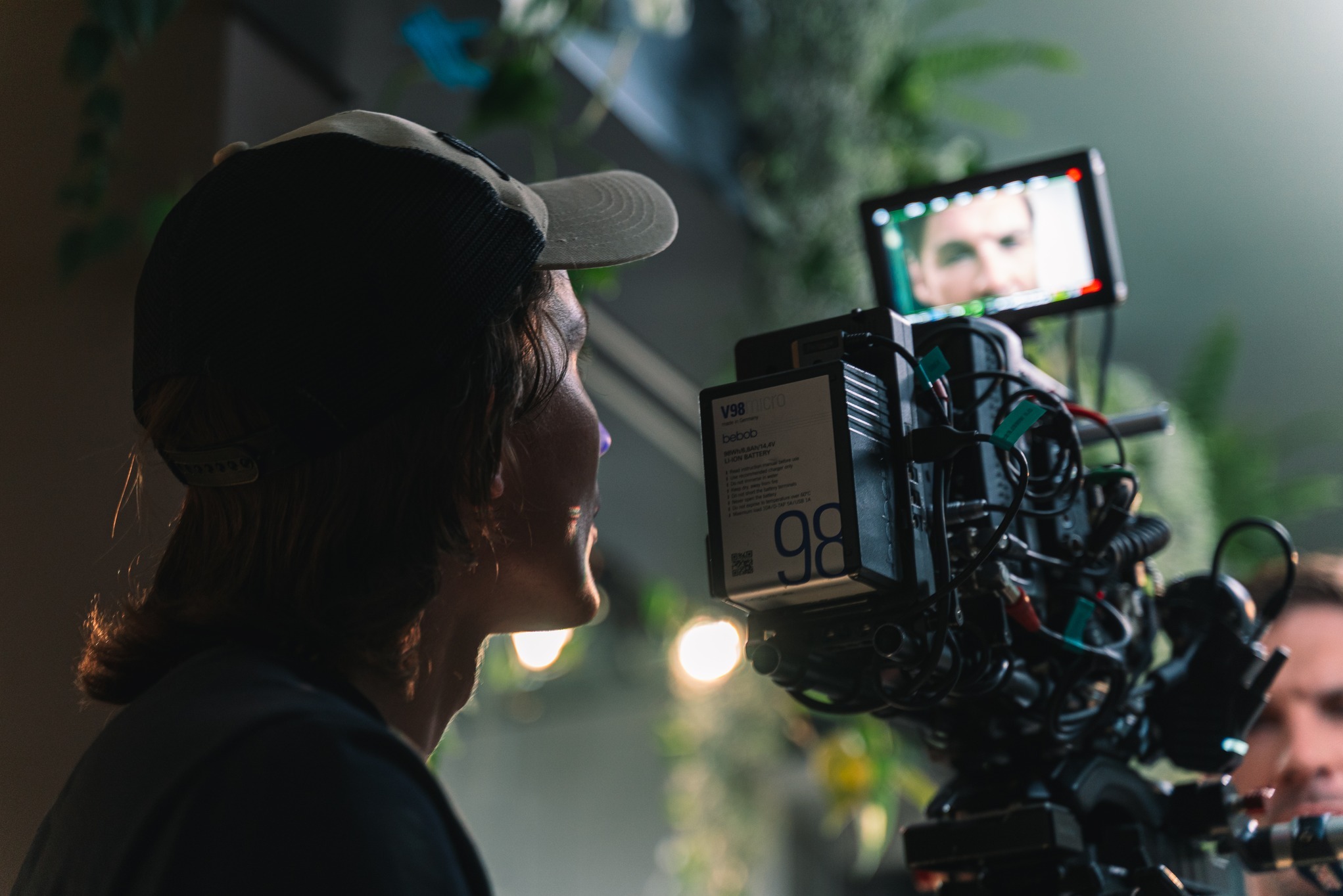 Operator kamery z Lublina filmuje scenę. Widoczny profesjonalny sprzęt, monitor z podglądem aktora i oświetlenie. Ujęcie zza pleców operatora, w tle dekoracje.